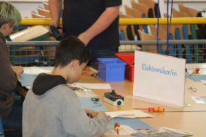 Schüler sitzt an einem Tisch und arbeitet an einem Elektronikprojekt.