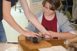 Ein Schüler arbeitet an einem technischen Gerät mit Anleitung.