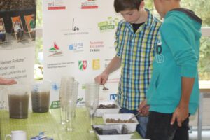 Schüler führen ein Experiment mit Erde und Wasser durch.