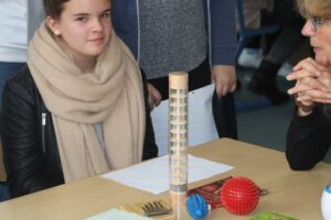 Schülerin sitzt an einem Tisch mit Experimentmaterialien.