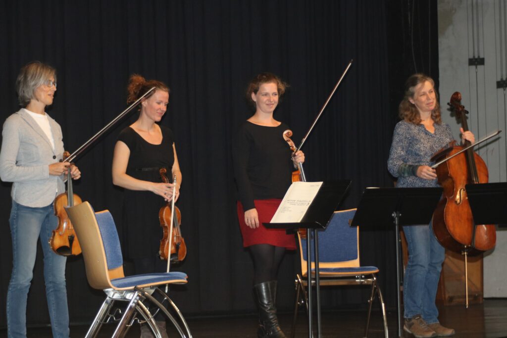 Vier Musikerinnen mit Streichinstrumenten stehen auf einer Bühne.