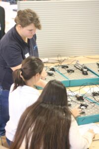 Schülerinnen arbeiten an einem Elektronikprojekt mit Kabeln und Bauteilen.