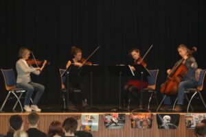 Vier Musikerinnen spielen auf der Bühne Geigen und ein Cello.