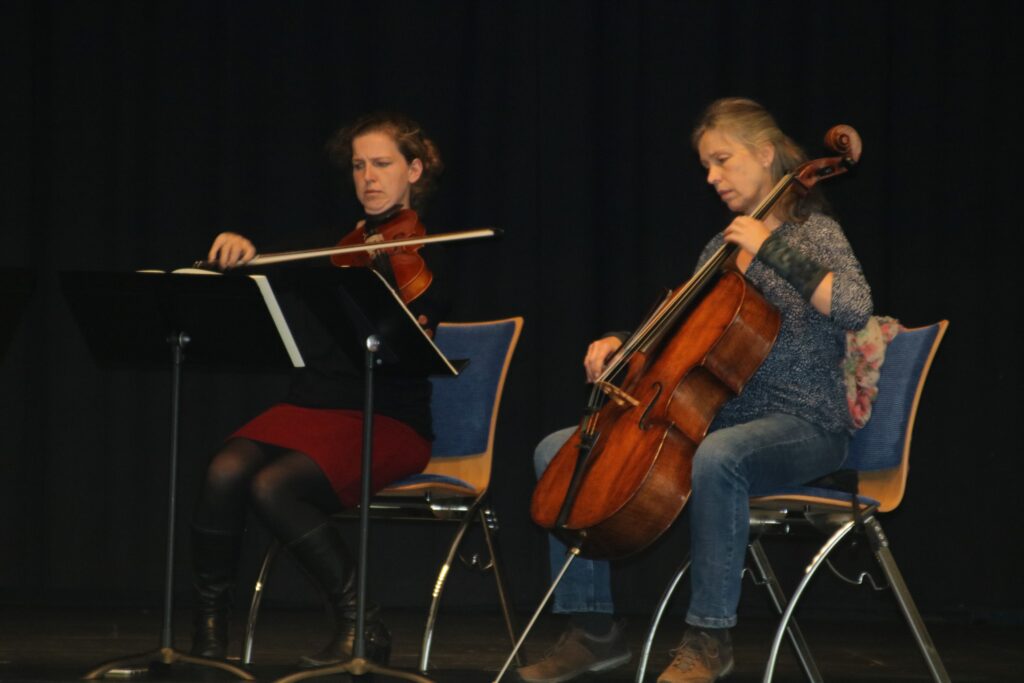 Zwei Musikerinnen spielen auf einer Bühne Geige und Cello.