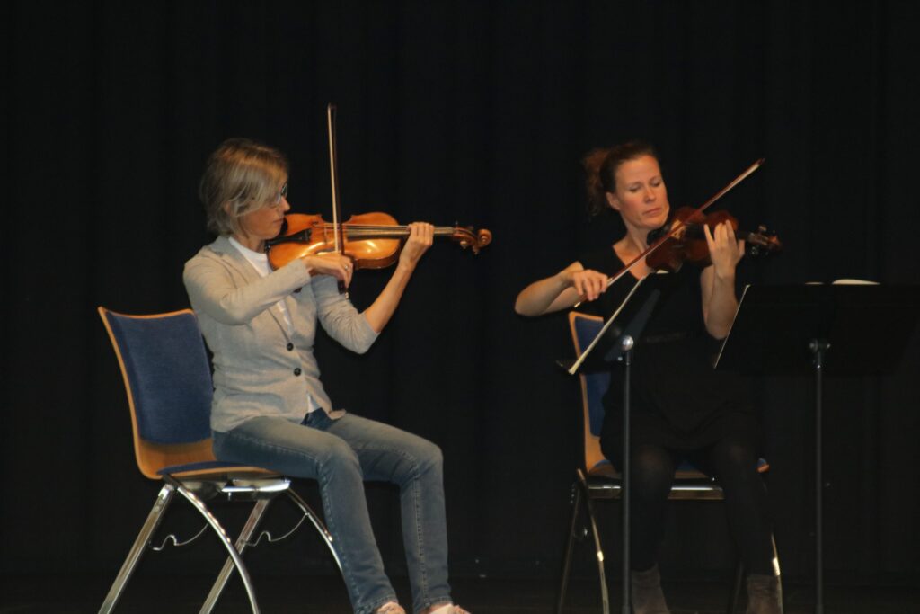 Zwei Frauen spielen auf der Bühne Violine.