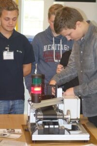 Schüler arbeiten an einer technischen Maschine und beobachten aufmerksam.