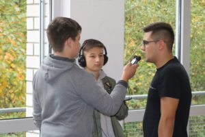Zwei Schüler interviewen einen dritten Schüler in der Schule.