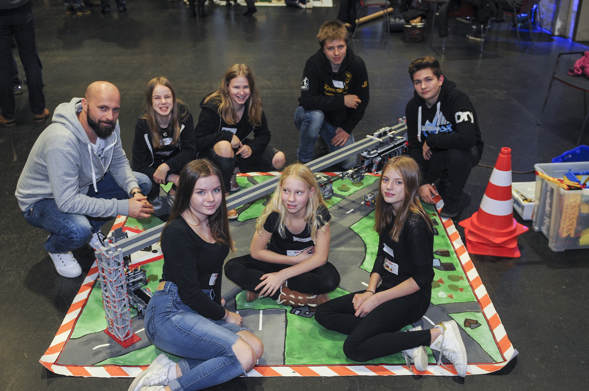 Gruppe von Schülern und einem Lehrer posiert auf einem Bodenbild mit einem Modell.