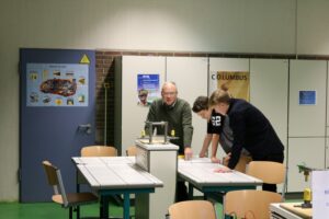 Lehrer und Schüler arbeiten gemeinsam an einem Tisch in einem Klassenraum.