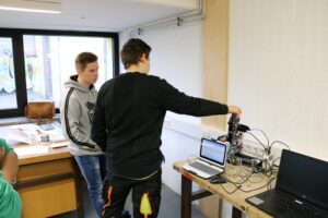 Zwei Schüler arbeiten an einem Roboter Projekt an einem Tisch in einem Klassenraum.