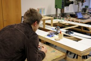 Schüler arbeitet an einem technischen Projekt mit verschiedenen Materialien.