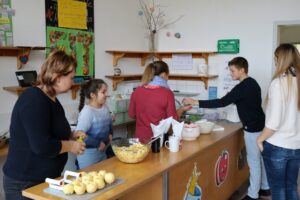 Personen bereiten in einer Schulküche gemeinsam Essen vor.