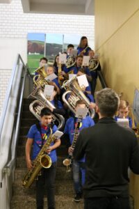 Schüler der Blaskapelle stehen auf einer Treppe und spielen Musikinstrumente.