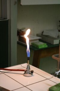 Bunsenbrenner mit blauem Flammenstrahl in einem Labor.
