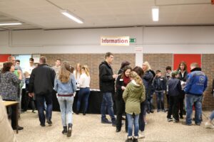 Menschen stehen an Ständen in einer Informationsmesse oder Veranstaltung.