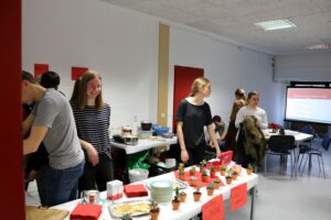 Schülerinnen und Schüler stehen an einem Tisch mit kleinen Pflanzen und Snacks.