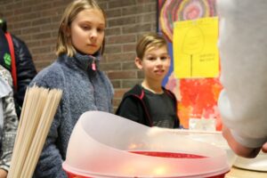 Zwei Kinder schauen neugierig auf ein Experiment mit Flüssigkeiten.