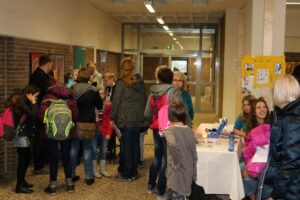 Schüler und Eltern stehen in einer Schule an einem Informationsstand.