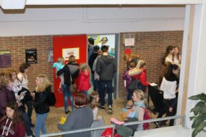 Schüler und Eltern im Flur der Schule, einige interagieren an einer Wand.