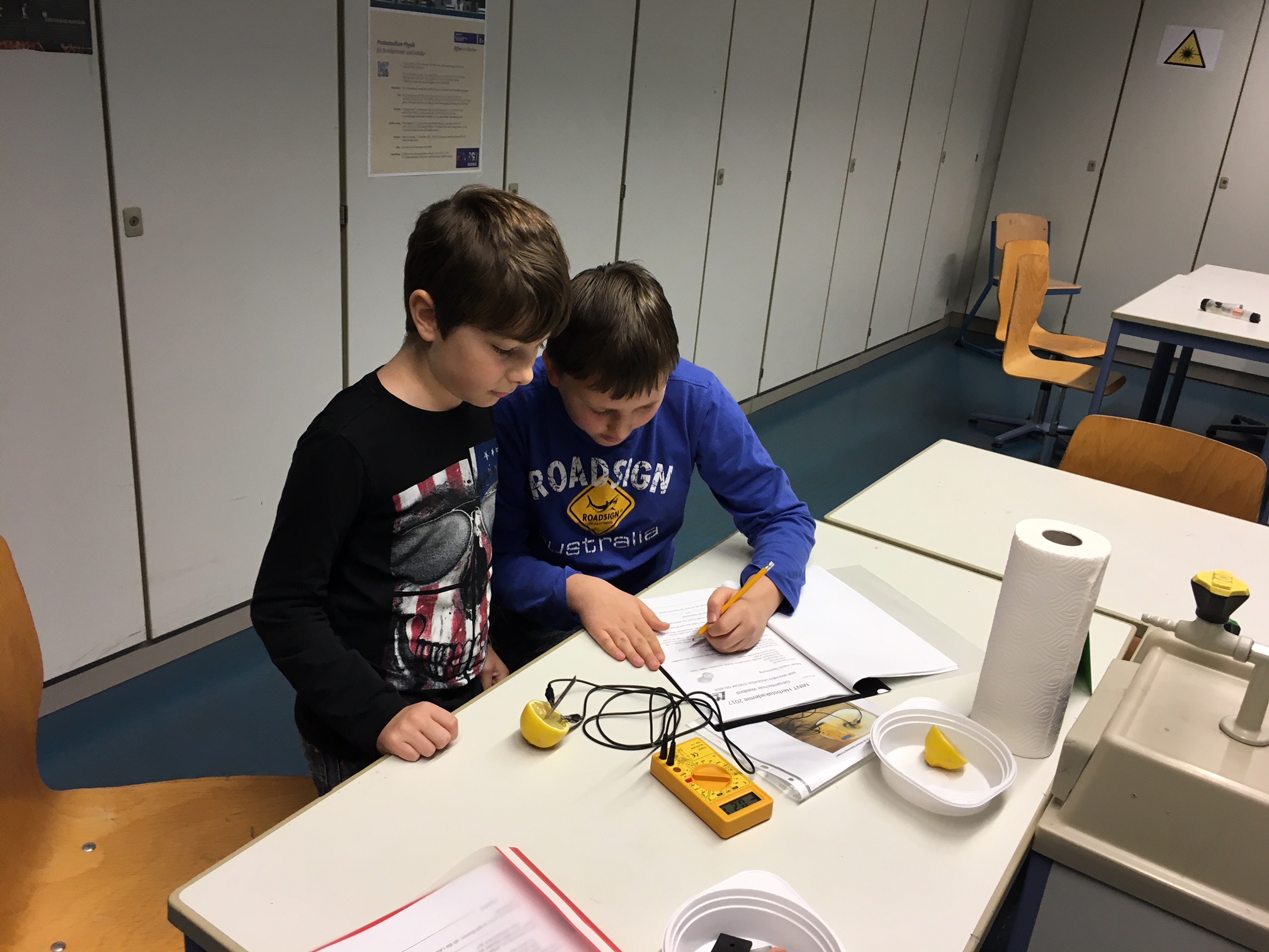 Zwei Schüler arbeiten gemeinsam an einem Tisch mit Notizen und Messgeräten.