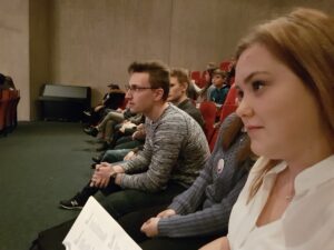 Zuschauer sitzen in einem Saal, bereit für eine Veranstaltung.