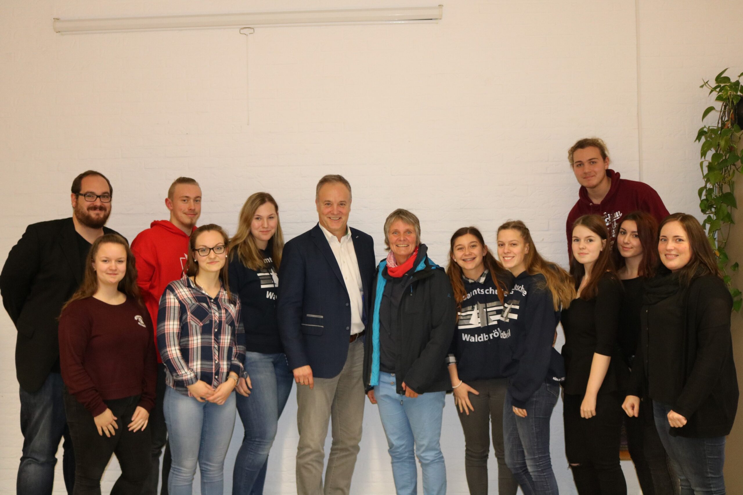 Gruppe von Schülern und Lehrern posiert für ein Foto in einem Klassenraum.