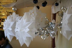 Papiersterne und glitzernde Dekoration hängen von der Decke.