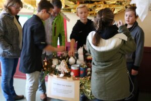 Schüler und Erwachsene gestalten einen Tisch mit Dekorationen und Bastelmaterialien.