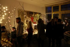 Weihnachtliche Veranstaltung mit dekorierten Tischen und Lichtern. Menschen interagieren.