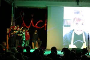 Schüler präsentieren auf der Bühne, im Hintergrund ein Video eines Kindes.