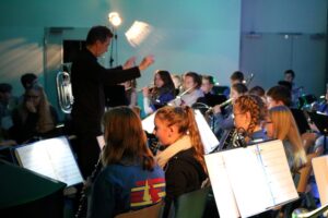 Musikensemble während einer Probe, der Dirigent leitet die Musiker an.