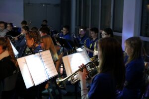 Schüler spielen in einer Schulband Instrumente in einem gut beleuchteten Raum.