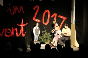 Aufführung mit Kindern vor einem Weihnachtsbaum und der Jahreszahl 2017.
