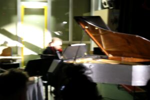 Ein Musiker spielt Klavier in einem schwach beleuchteten Raum.