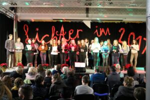 Schüler stehen auf der Bühne bei einer Veranstaltung mit Publikum.