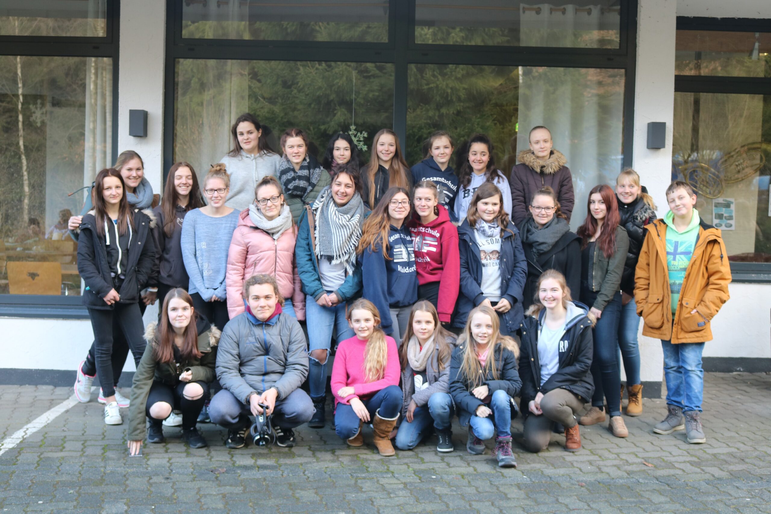 Gruppe von Schülerinnen und Schülern posiert vor einem Gebäude im Freien.