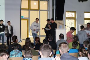Schüler erhalten Preise auf einer Schulveranstaltung in einem Auditorium.