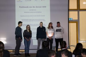 Sechs Schüler stehen auf einer Bühne vor einem Publikum.