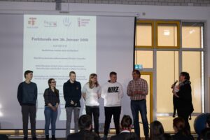 Gruppenvorstellung von Schülern bei einer Veranstaltung auf der Bühne.