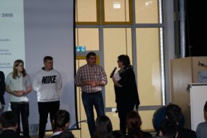 Schüler und Lehrer stehen auf der Bühne während einer Veranstaltung.
