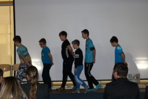 Sechs Jungen führen eine Choreografie auf einer Bühne vor.