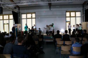 Schüler führen auf einer Bühne eine Präsentation vor Publikum auf.