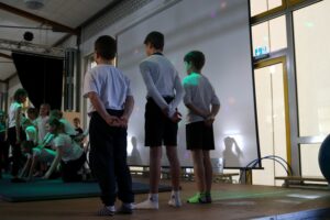 Kinder stehen auf der Bühne und beobachten eine Aufführung.