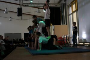 Kinder führen eine Turnvorführung auf einer Bühne durch.