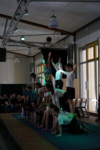 Schüler zeigen eine Turnvorführung auf einer Bühne vor Publikum.