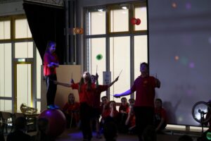 Zirkusaufführung mit Artisten, die jonglieren und auf einem Ball stehen.