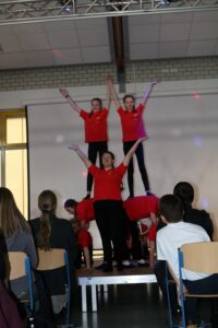 Tanzgruppe führt eine Akrobatiknummer auf einer Bühne vor Publikum auf.