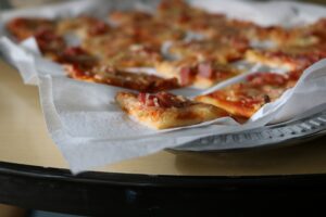 Stück Pizza auf einem Teller mit Backpapier.