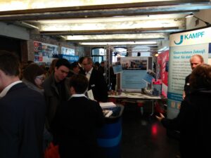 Messe mit mehreren Ständen und Besuchern, Menschen im Austausch.