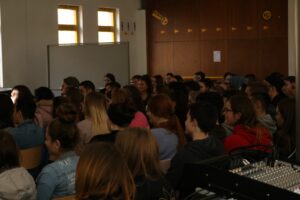 Schülerinnen und Schüler hören in einem Klassenraum einem Vortrag zu.
